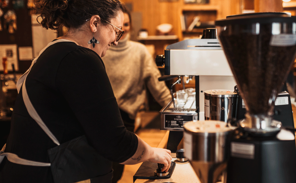 A woman making coffee at an espresso machine