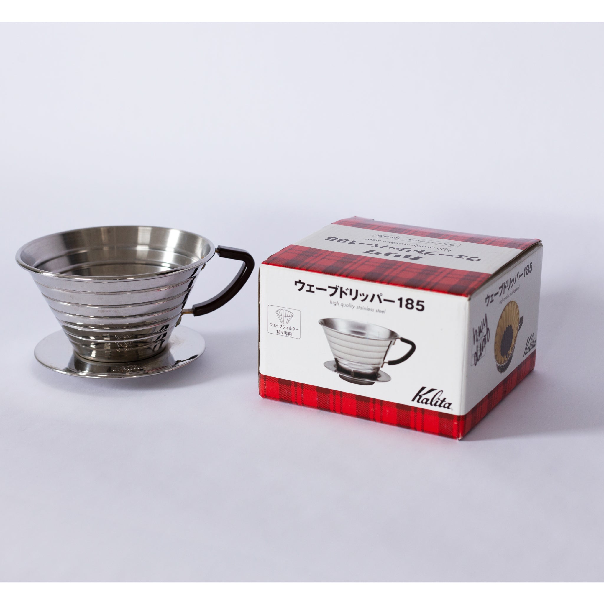 A steel coffee brewer next to it's packaging.